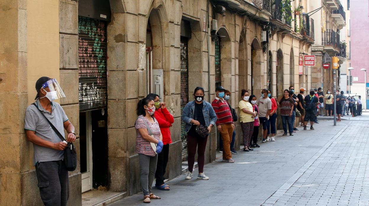 Varias personas de la comunidad filipina de Barcelona hacen cola para recoger comida frente a la asociación EAMISS de Barcelona,