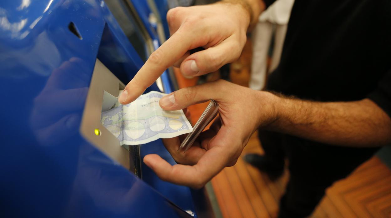 Un pasajero introduce un billete para adquirir el abono de transporte mensual en Madrid