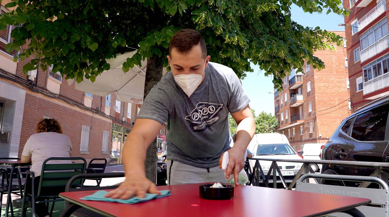 Una camarero limpia y desinfecta la terraza de su bar en Valladolid