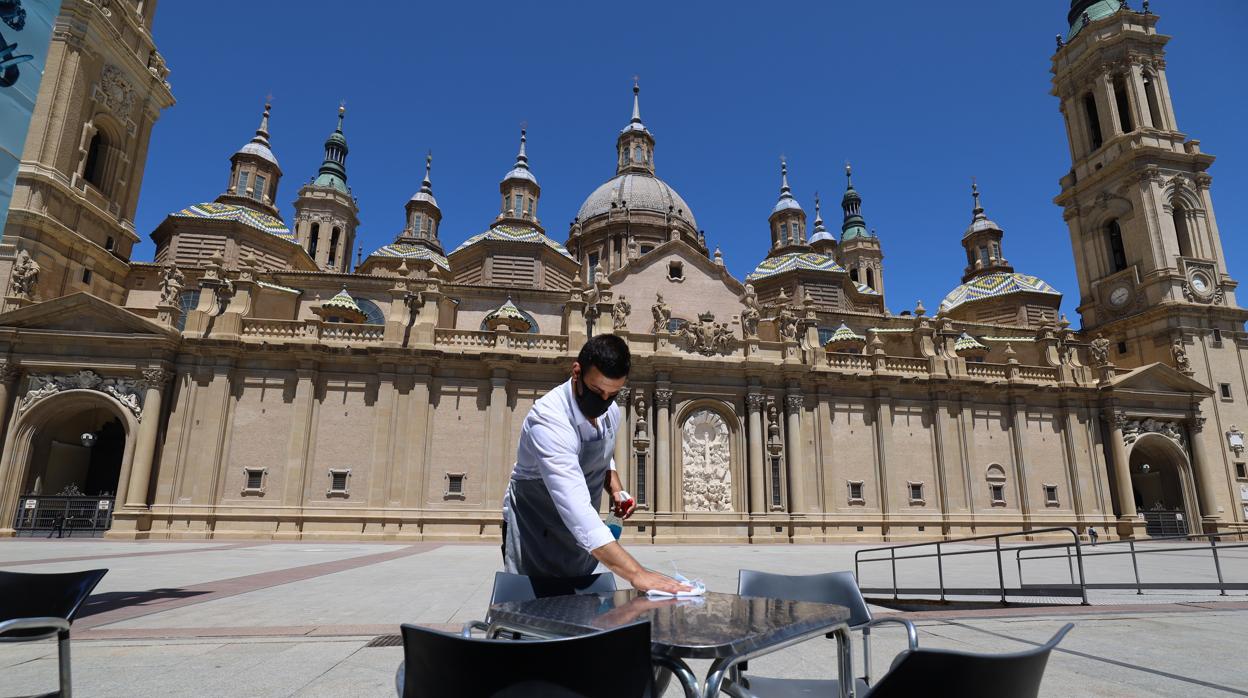 Un camarero limpiando las mesas de una terraza en la Plaza del Pilar de Zaragoza, que presentaba ese desangelado aspecto este viernes a mediodía