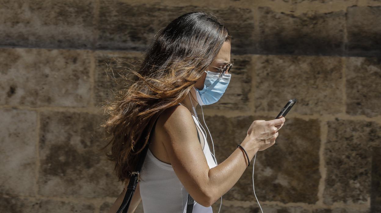 Una chica con mascarilla por el centro de Valencia