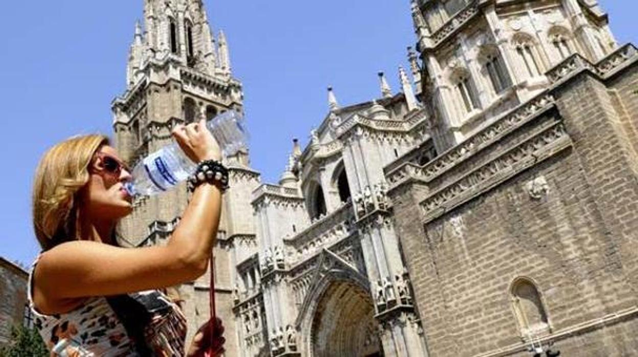 Una turista bebe agua delante de la catedral de Toledo