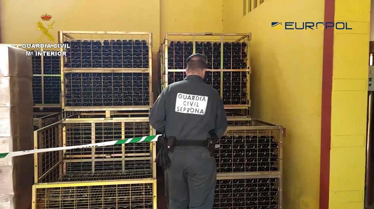 Un agente del Seprona de la Guardia Civil precinta contenedores con botellas de vino