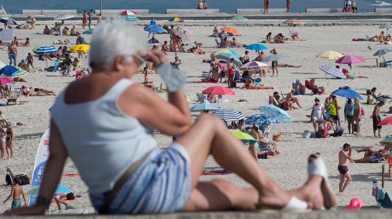 Una persona sentada frente a una playa de A Mariña el lunes