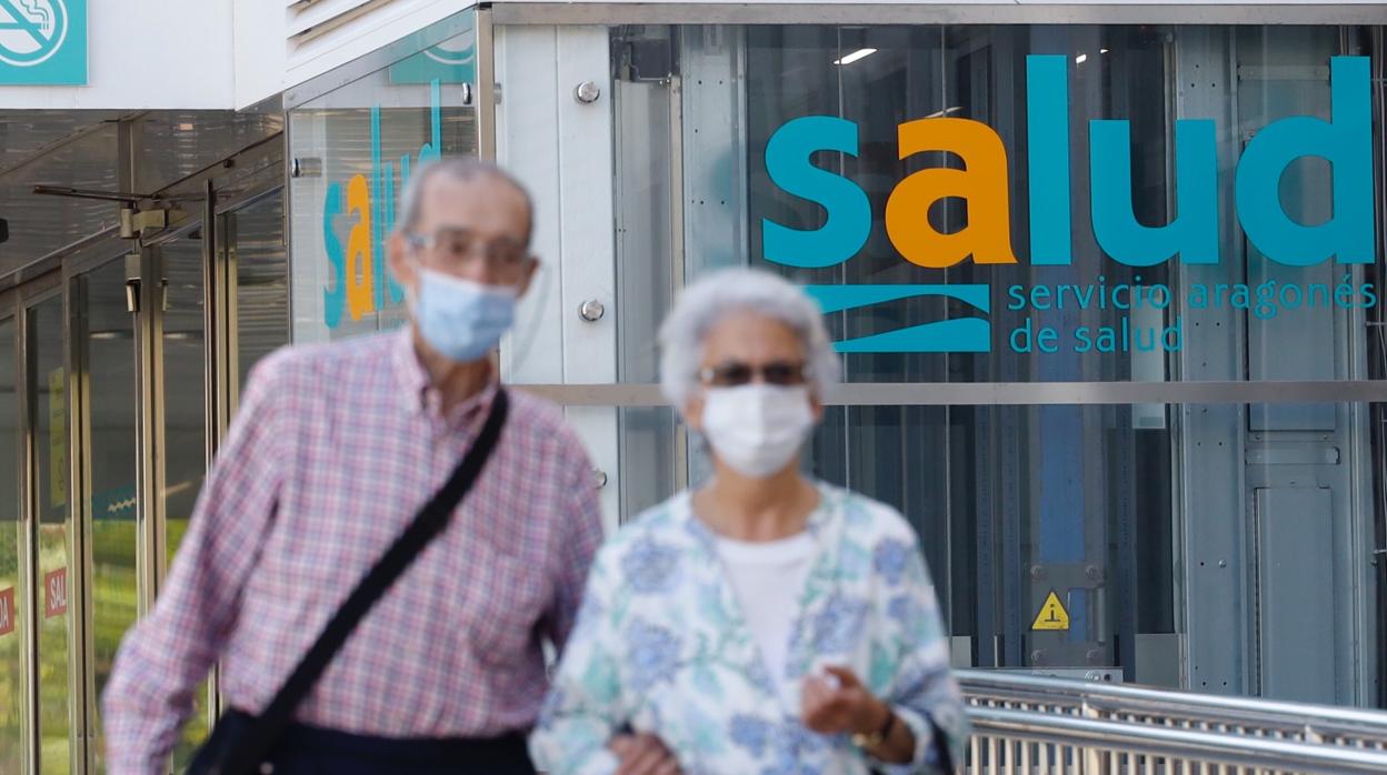 Dos ciudadanos con mascarilla pasan por delante de un hospital de Zaragoza