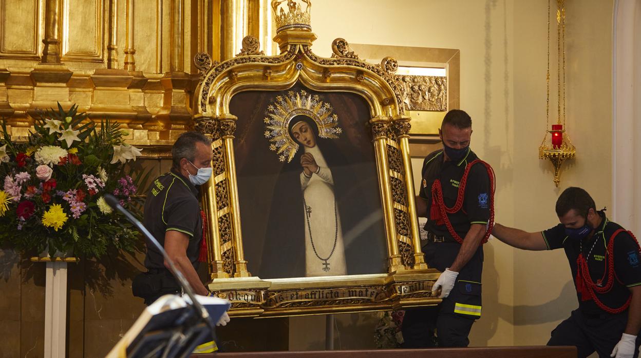 Los bomberos, con las mascarillas, en el descenso del cuadro de la Virgen de La Paloma