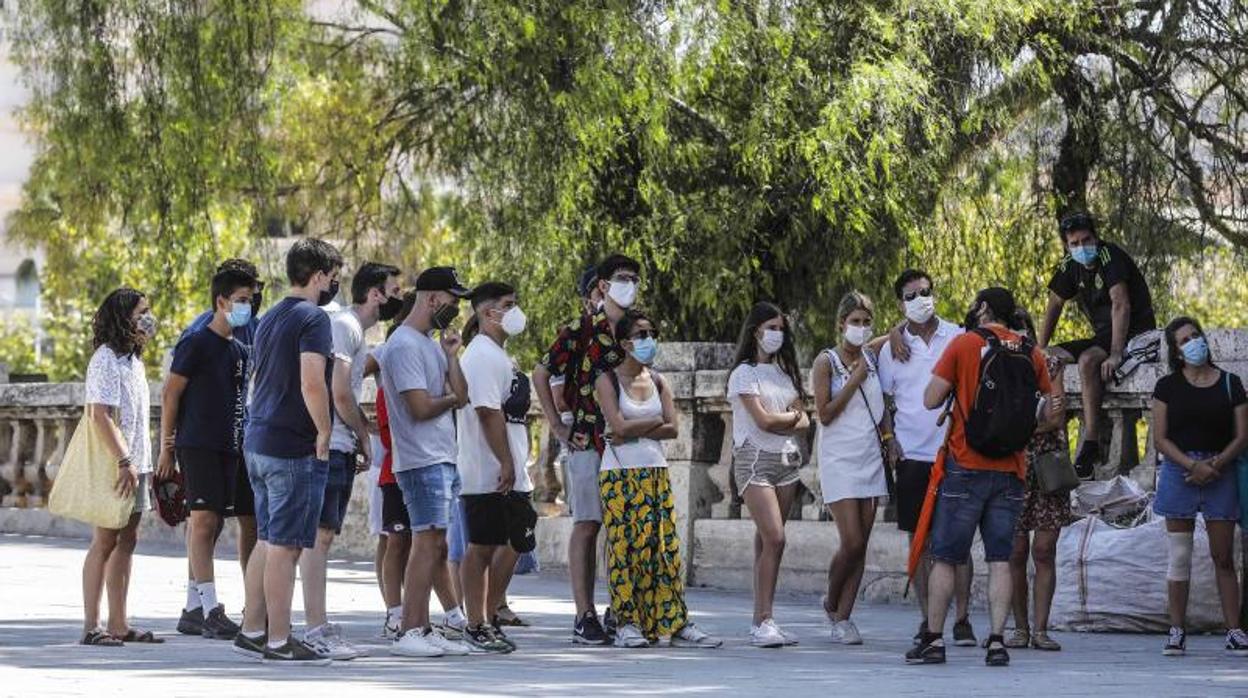 Turistas con mascarilla explican las expicaciones de un guía en Valencia