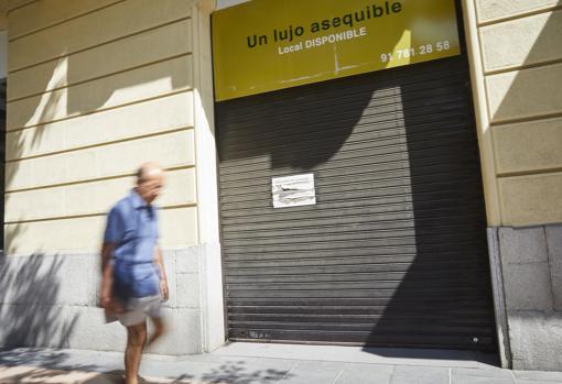 Un hombre cruza frente a un local cerrado y disponible en la Milla de Oro