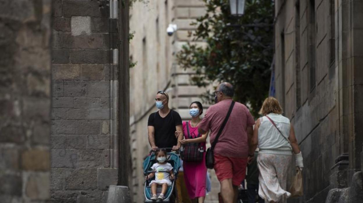 Una pareja, con una niña con mascarilla, este lunes por el barrio Gótico de Barcelona