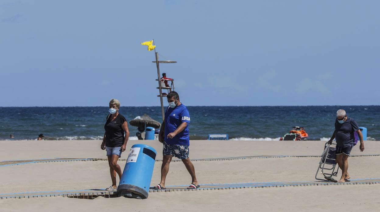 Varias personas con mascarilla en la playa del Cabanyal de Valencia