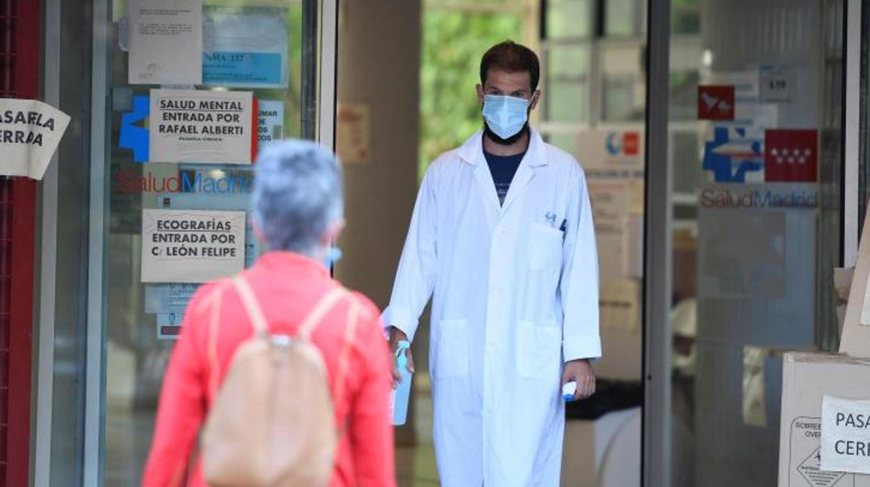 Un sanitario recibe a una paciente termómetro en mano en el centro de salud Federica Montseny en el distrito de Puente de Vallecas en Madrid