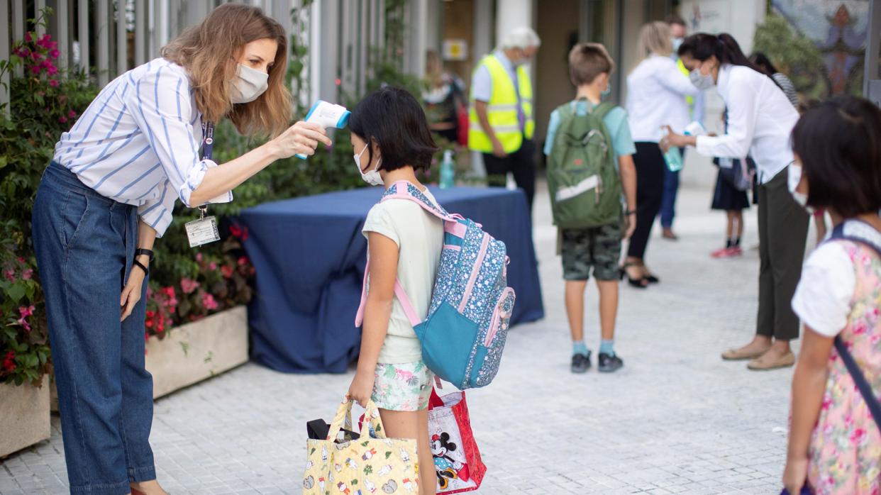 Una profesora toma la temperatura a una alumna en el acceso a una escuela en Barcelona