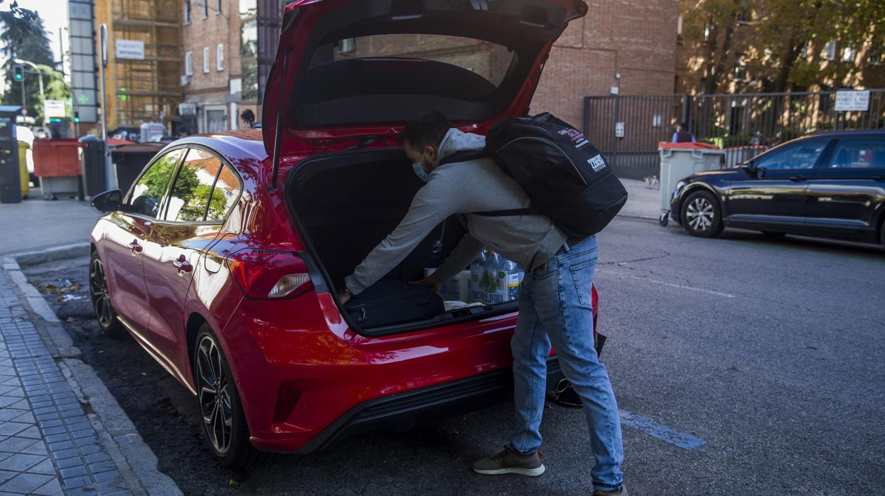 Un hombre carga una maleta y diversas provisiones en el maletero de su coche, ayer/ Entran en vigtor las restricciones en Madrid: ¿Qué se puede hacer y qué no?