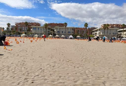 Varias personas retiran banderas españolas en la playa valenciana