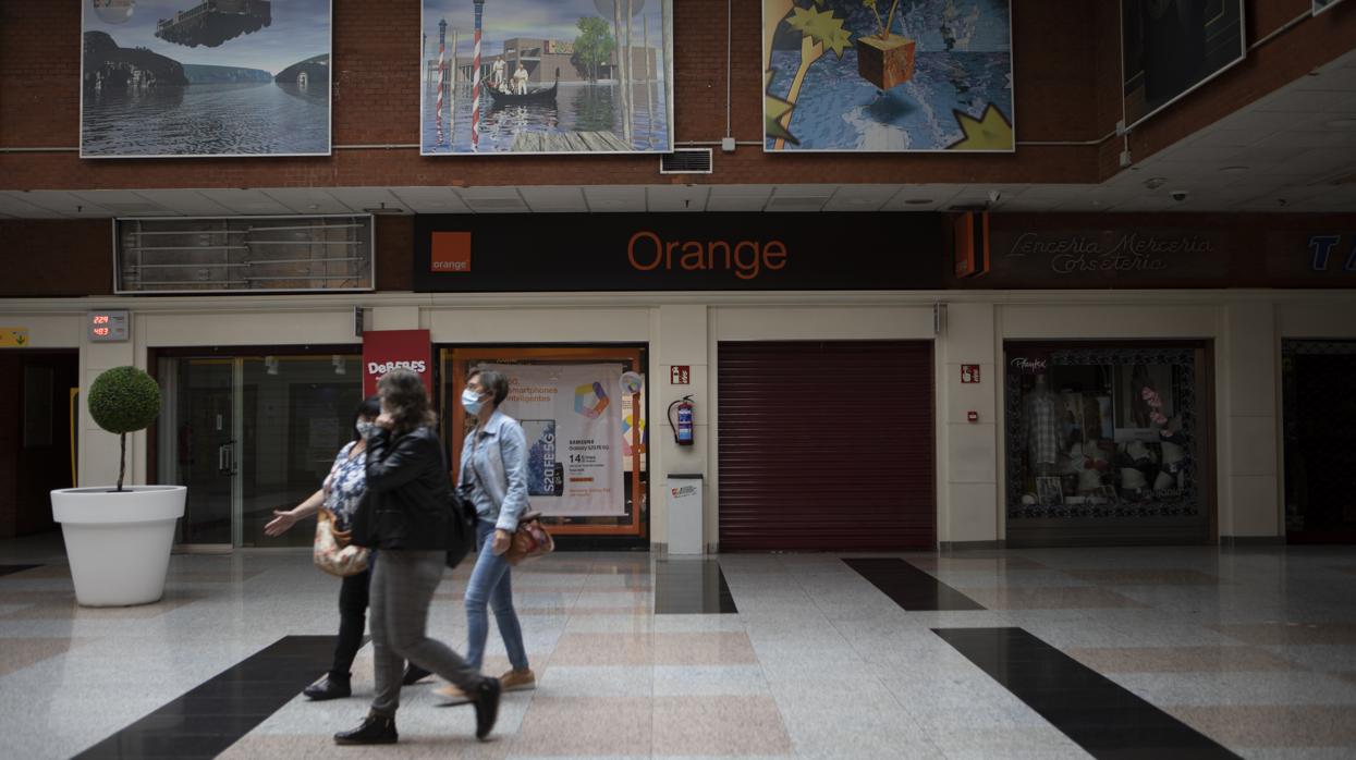 Tres personas pasan por delante de la tienda de telefonía asaltada el pasado sábado