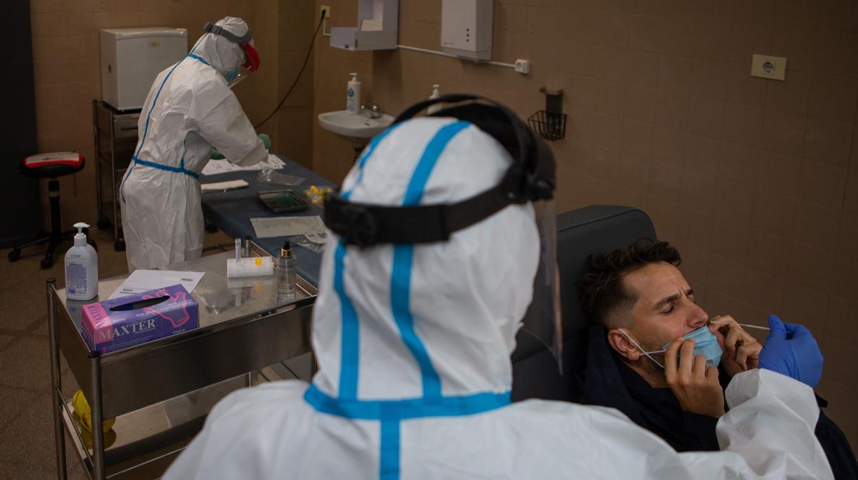 Una pofesional sanitaria realiza una prueba PCR a un paciente en Barcelona.