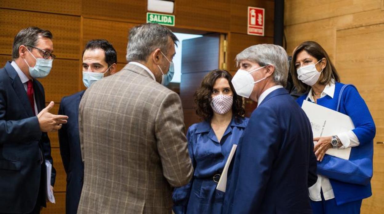 La presidenta de la Comunidad, Isabel Díaz Ayuso, habla con su equipo en el pleno de la Asamblea de Madrid