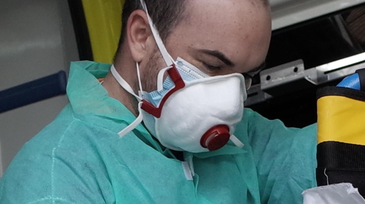 Sanitario provisto de dos mascarillas mientras realiza tareas de desinfección en una ambulancia