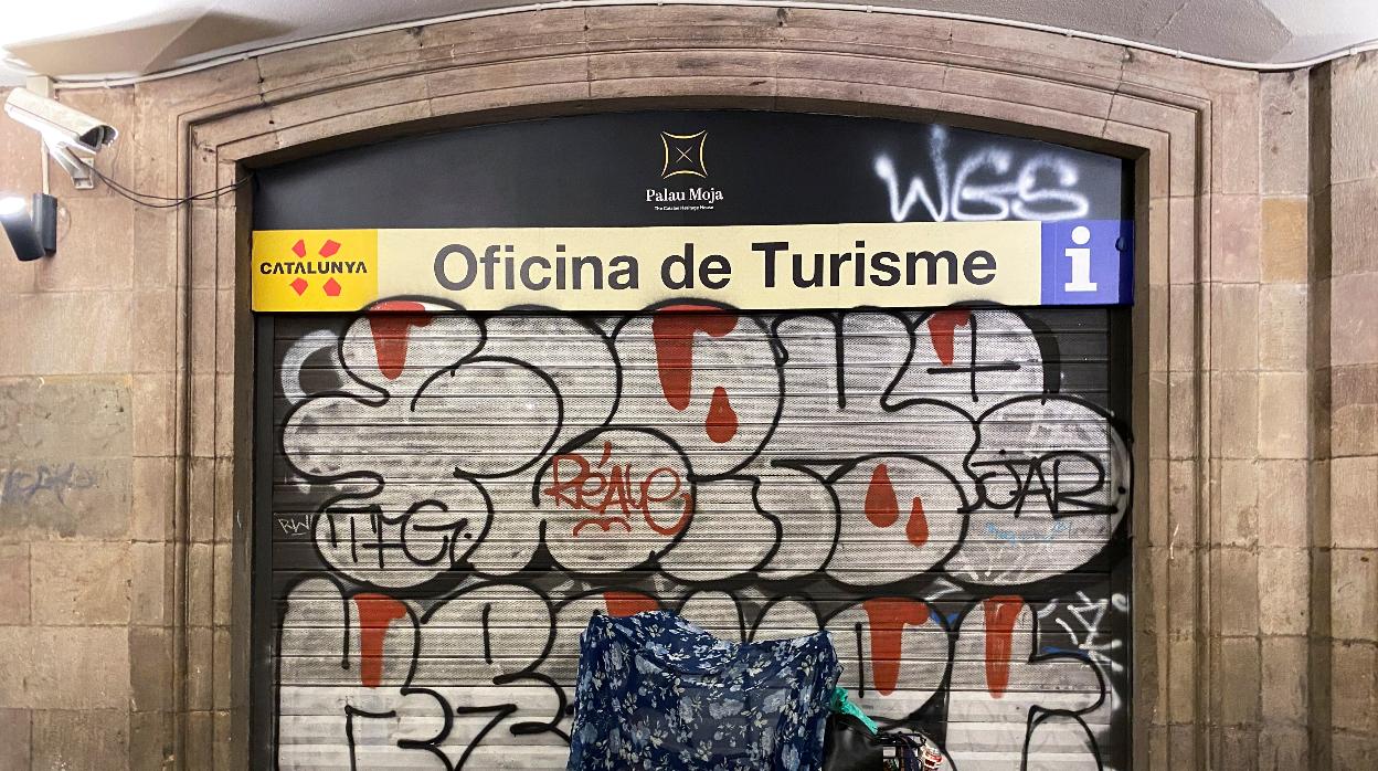 Una persona sin hogar duerme ante una oficina de turismo de Barcelona