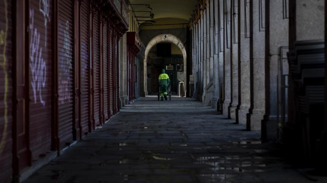 Un operario de limpieza recoge desperdicios en los soportales de la Plaza Mayor