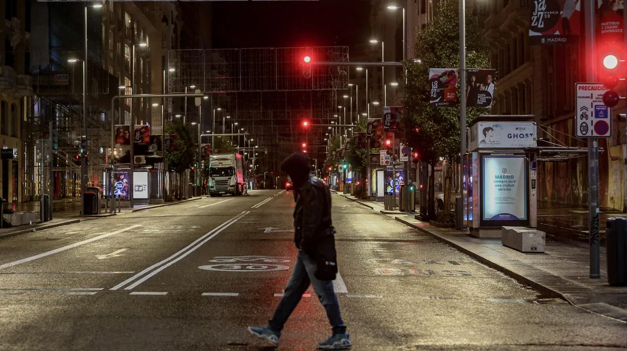 Un hombre cruza una Gran Vía solitaria durante la primera noche del «toque de queda»