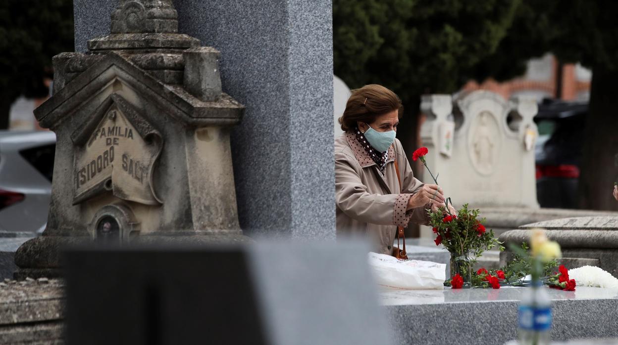 Una mujer deja flores en un cementerio durante la pandemia