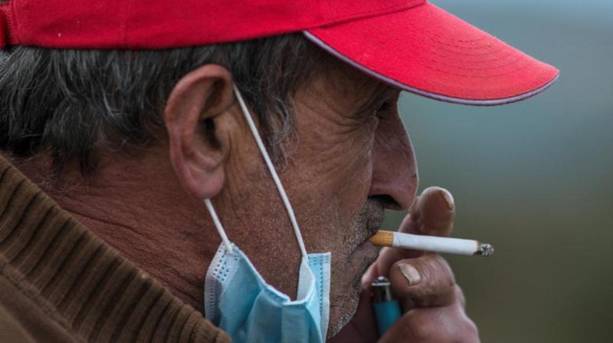 Un hombre, con la mascarilla bajada, fuma un cigarillo en Orense