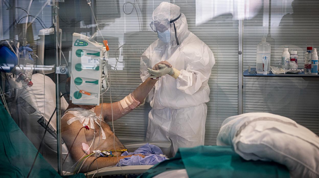 Imagen de un sanitario atendiendo a un paciente en la UCI durante la primera ola del coronavirus