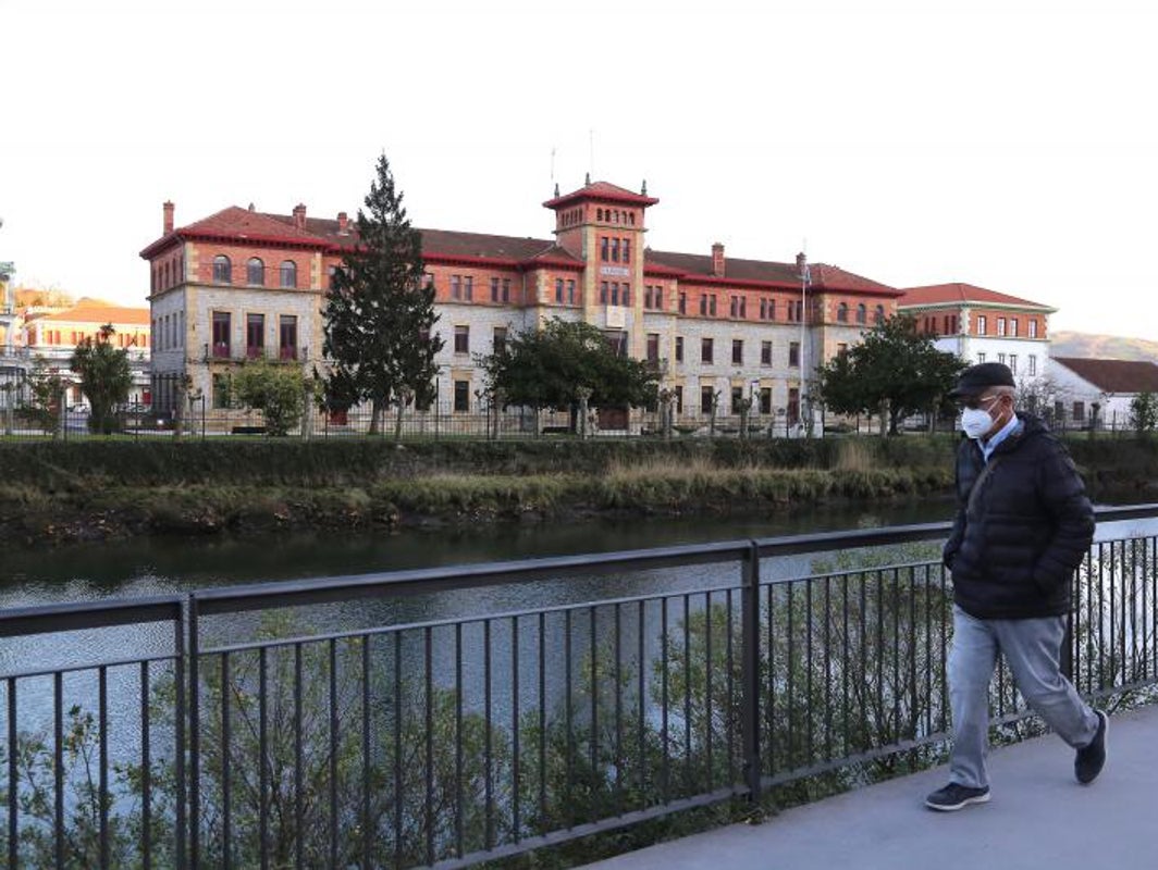 Una persona pasea por el margen del río Urumea, frente al acuartelamiento de Loyola