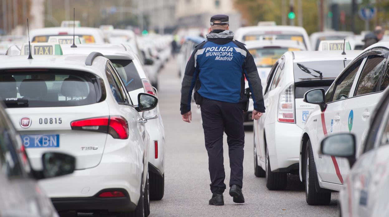 Un policía municipal camina entre decenas de taxis durante la protesta en el centro de la capital