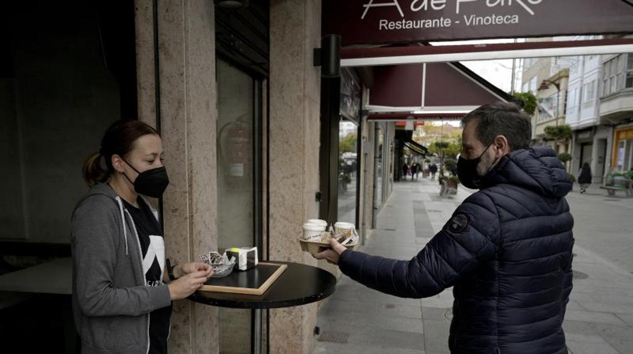 Un hombre recoge cafés para llevar en un restaurante de Bergantiños (La Coruña)