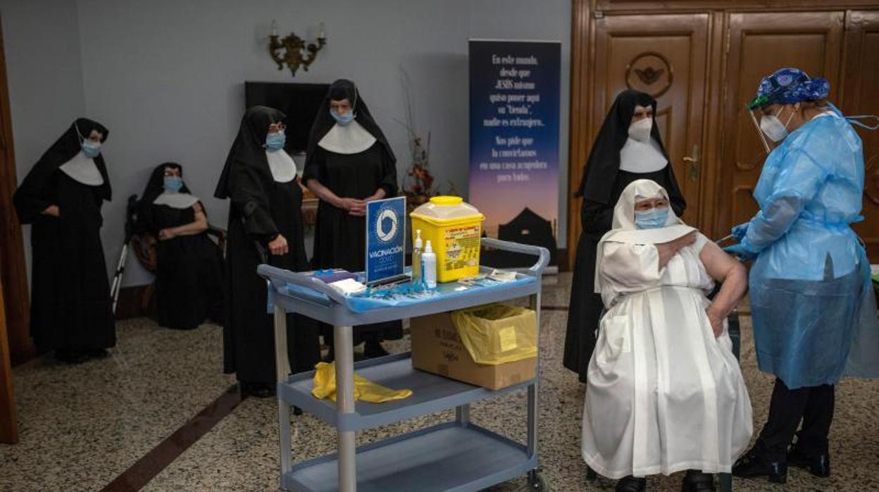 Una sanitaria vacuna a una monja contra el coronavirus, en el interior de la Residencia San José