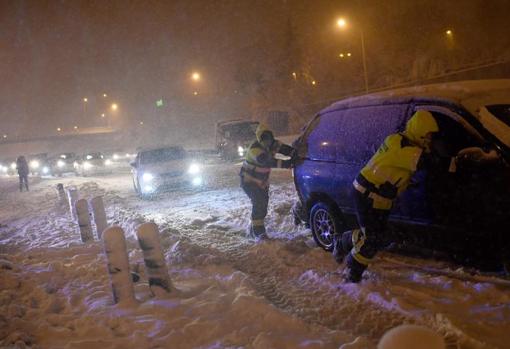 Dos hombres empujan un vehículo, en medio de la nevada