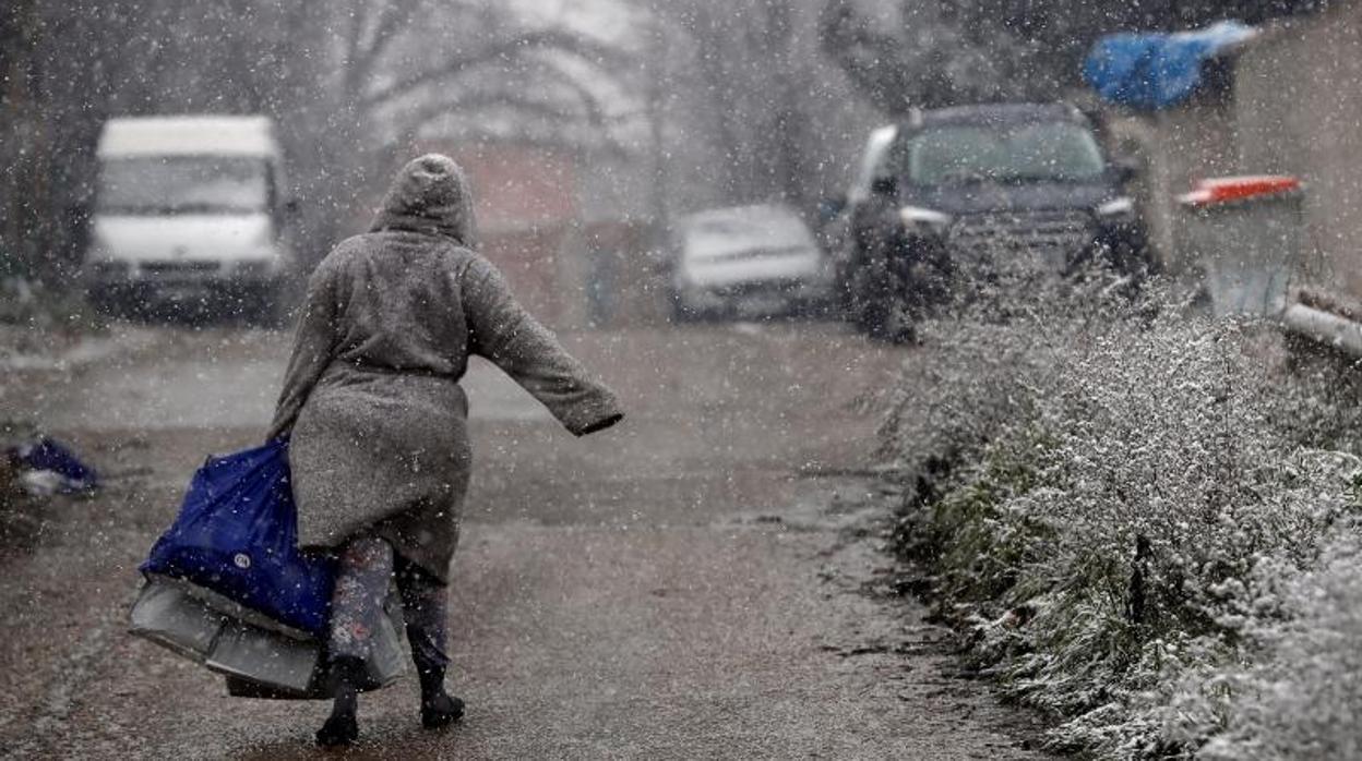 Una mujer camina bajo la nieve en el sector de la Cañada Real que lleva tres meses sin luz
