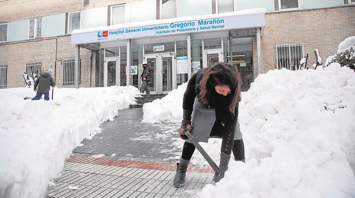 Varias personas limpian la nieve de una de las entradas del Gregorio Marañón