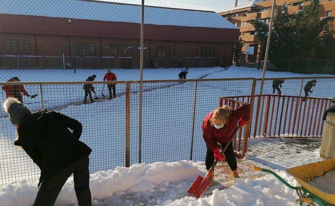 Padres y profesores rertiran con palas la nieve acumulada en el colegio Infantes de Toledo