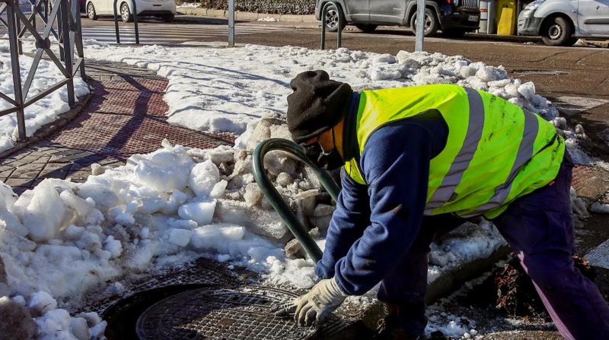 Un operario limpia nieve del alcantarillado de Madrid antes de que comiencen las lluvias en la capital