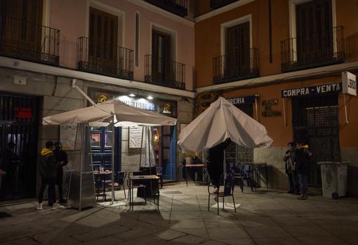 Un restaurante de la plaza del Dos de Mayo recoge las sombrillas antes de cerrar