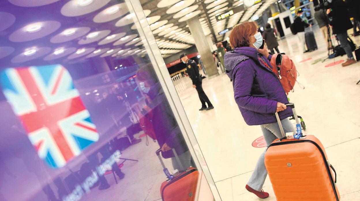 Una pasajera con mascarilla, ante una pantalla informativa en el aeropuerto de Barajas