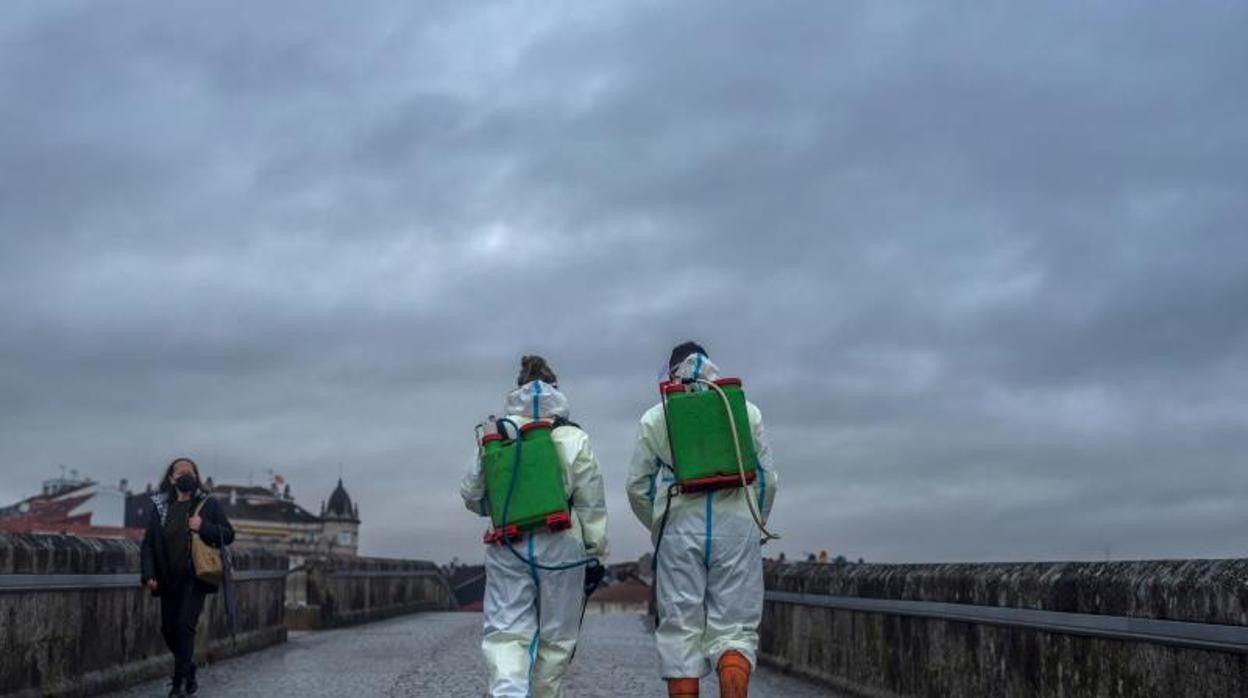 Dos operarios desinfectando el Puente Romano de Orense