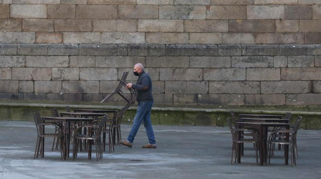 Un hostelero retira las sillas de su terraza en la Plaza de la Quintana de Santiago