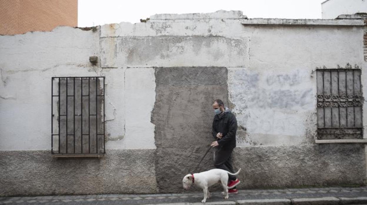 Un hombre pasea a su perro frente a la fachada donde se conserva el dintel de 1578, en la calle de Orión, 20, en el casco histórico de Barajas