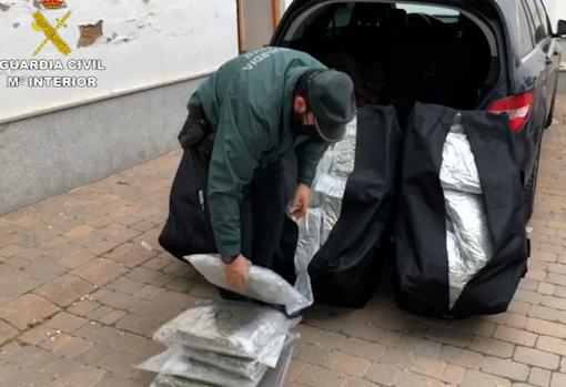 Un agente de la Guardia Civil descargando los 90 paquetes de marihuana que llevaba el coche