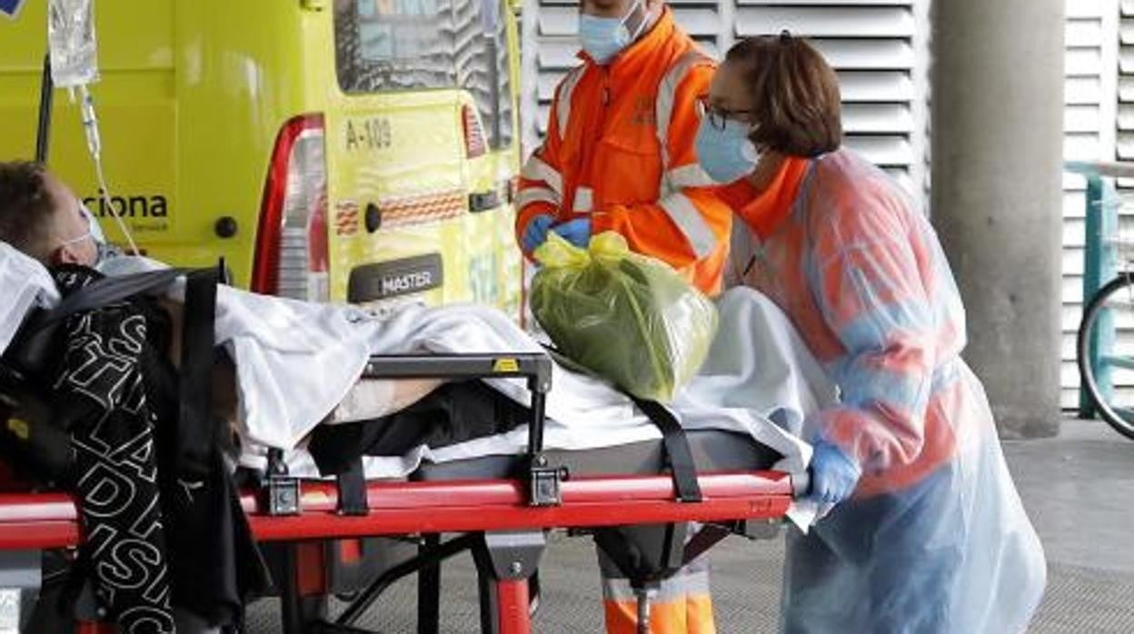 Una sanitaria traslada a un enfermo protegida con una bata desechable