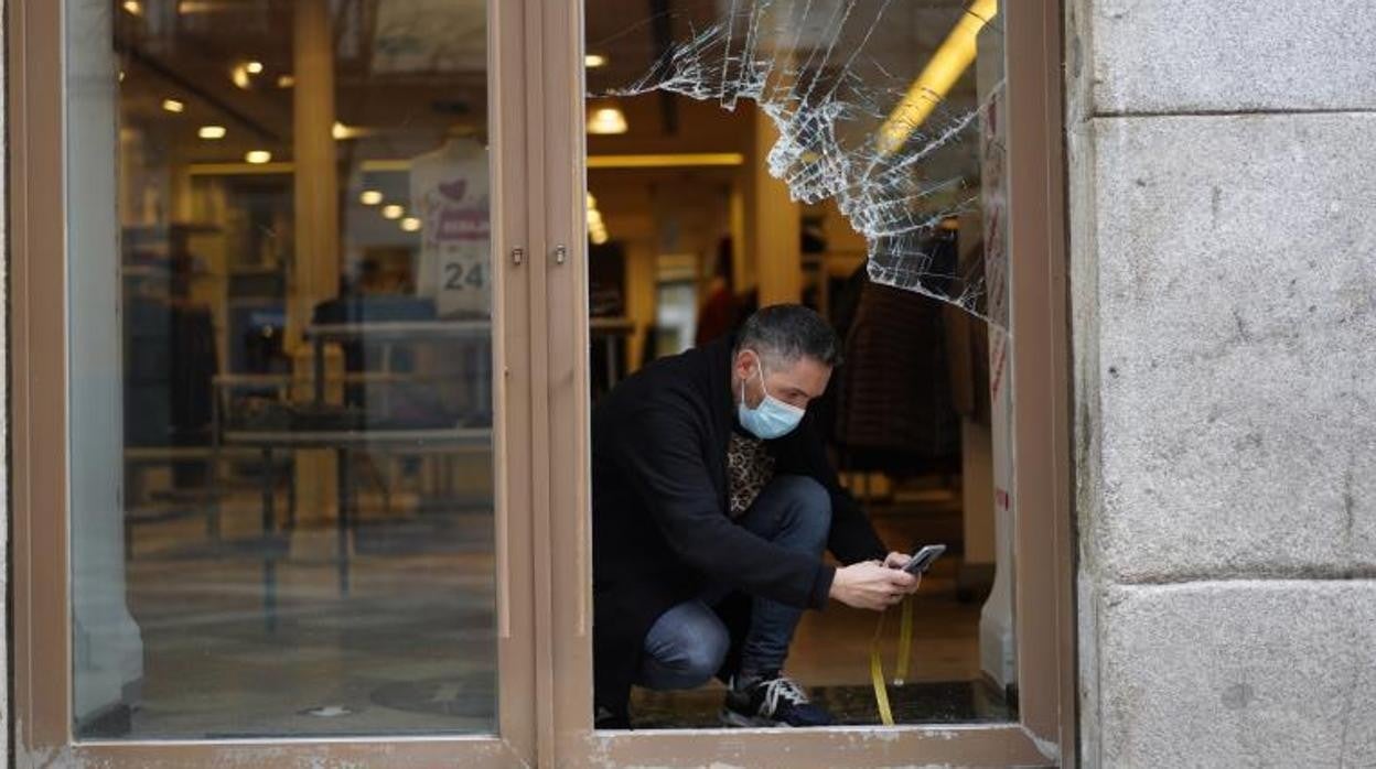 Un comerciante de la calle Arenal fotografía los desperfectos en su local