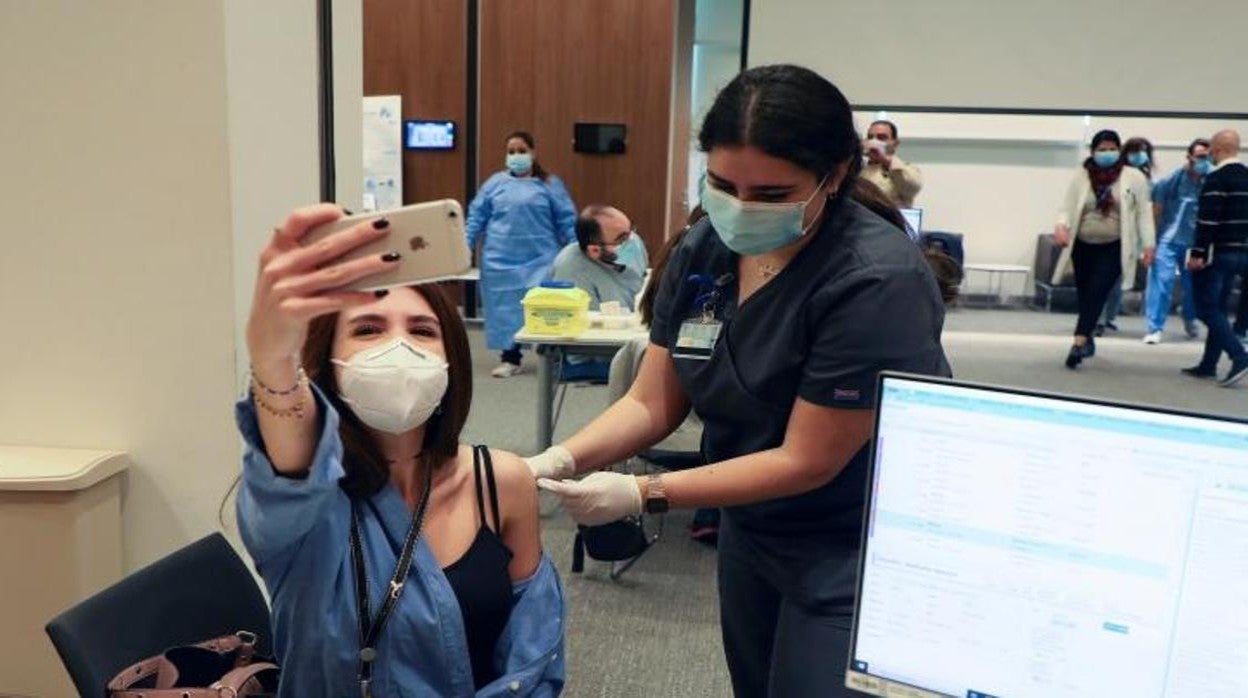 Una mujer se hace un selfie mientras le están poniendo la vacuna