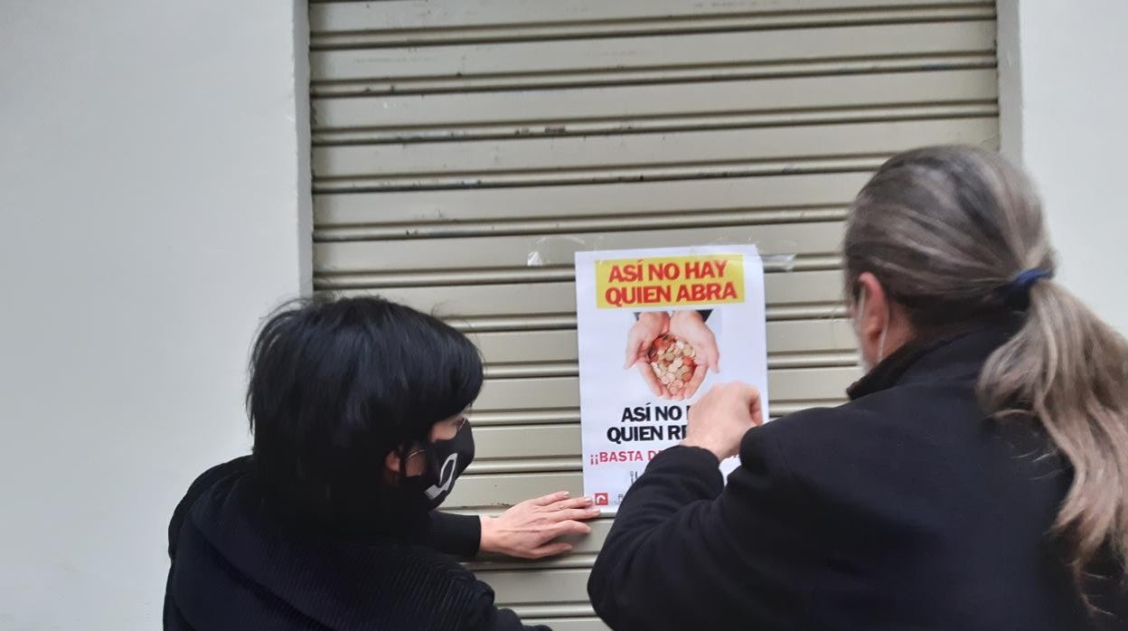 Dos hosteleros pegan carteles durante la protesta de este martes en Valencia