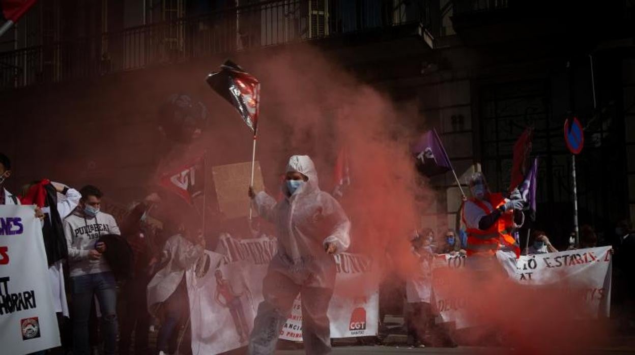 Una mujer sostiene una bandera vestida con un Equipo de Protección Individual