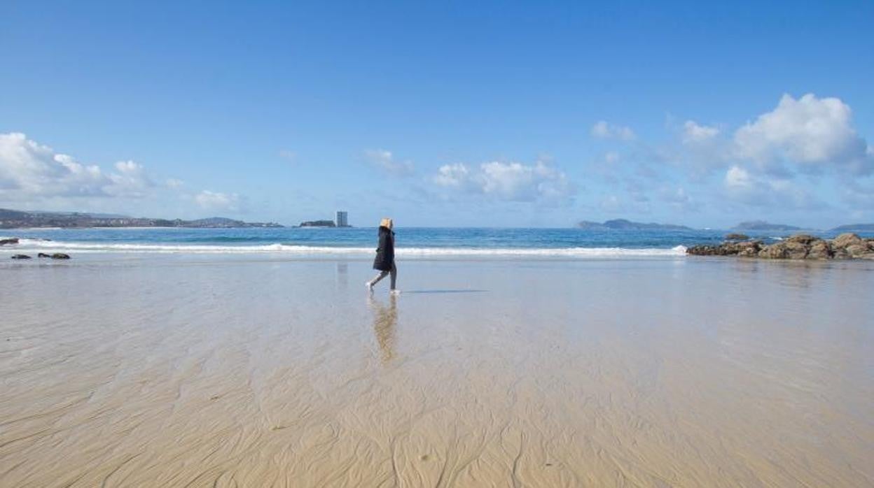 Una mujer paseando por la playa de Samil, en Vigo