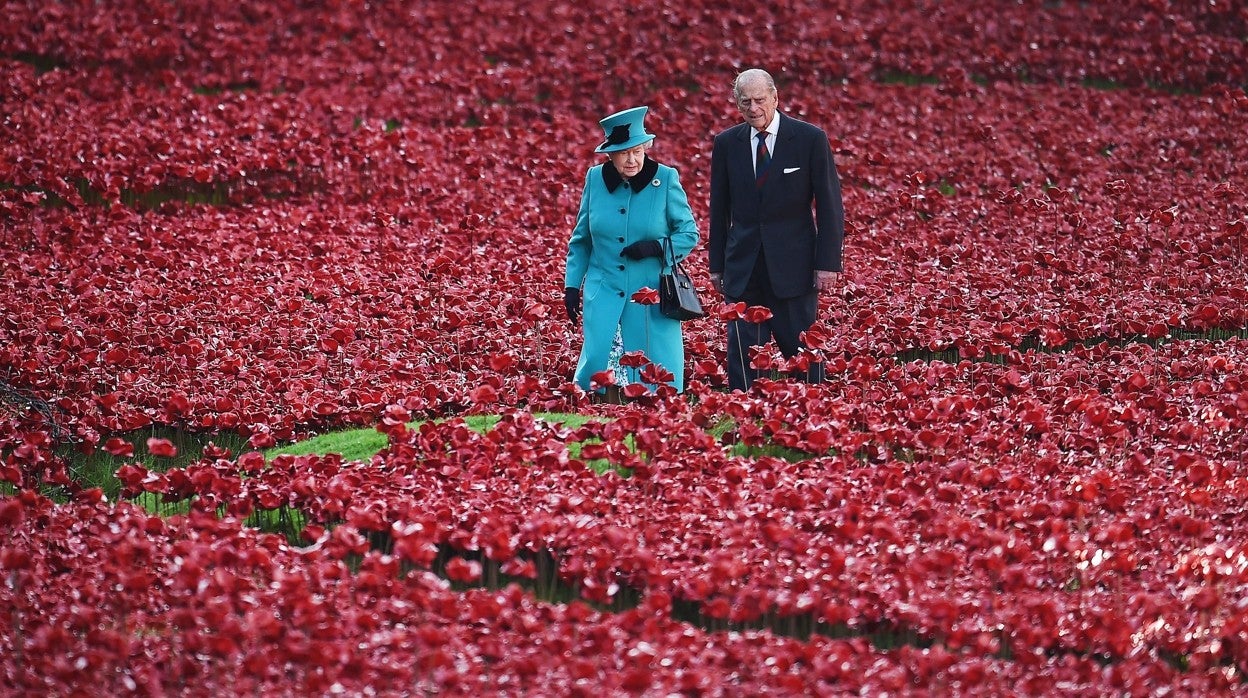 La Reina de Inglaterra y el Príncipe Felipe, en 2014, pasean por un campo de amapolas artificiales en homenaje a las víctimas de la I Guerra Mundial